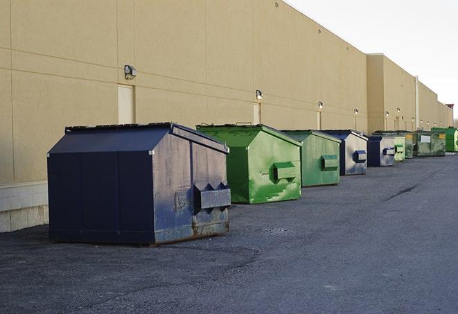 a construction worker unloading debris into a blue dumpster in Danvers, MA